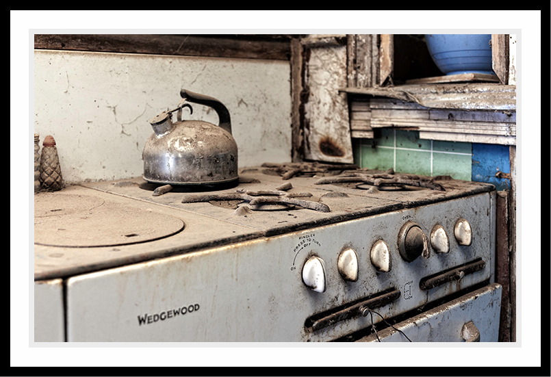 Old stove with kettle on the gas burner.